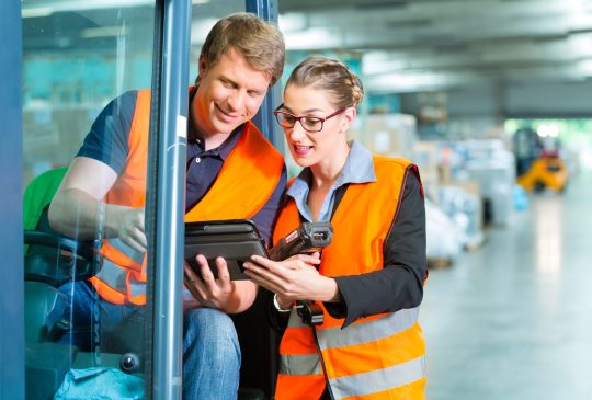 Logistics Teamwork - forklift driver, Worker or warehouseman and his coworker with scanner at warehouse of freight forwarding company